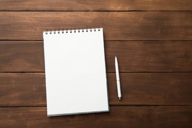 Boş defter ve kalem ahşap masada.