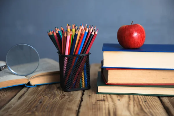 books with pencils and apple on tabl