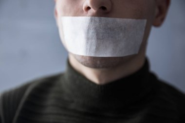 Konuşmasını engellemek için ağzı bantlı bir adam.
