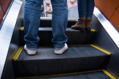 İnsanlar bir binada yürüyen merdivende duruyorlar.