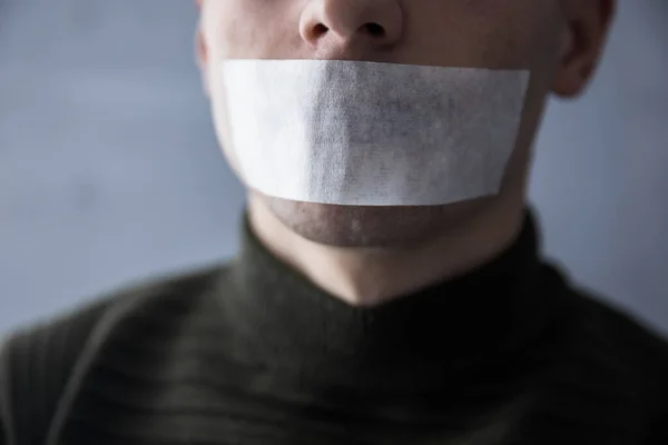 Konuşmasını engellemek için ağzı bantlı bir adam.