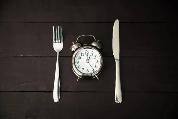 Alarm clock with fork and knife on the tabl