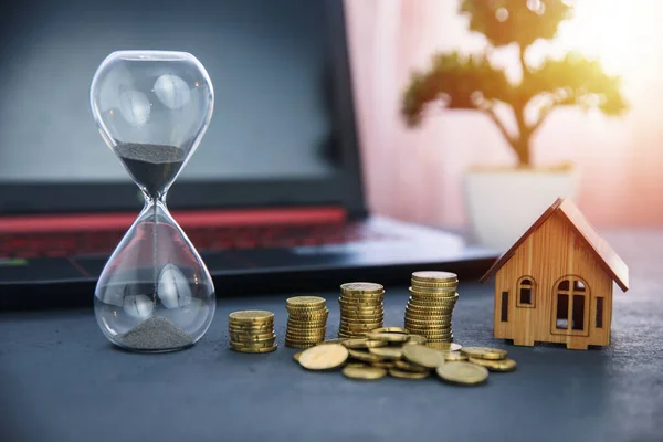 Üzerinde bozuk para ve ev modeli olan kum saati.