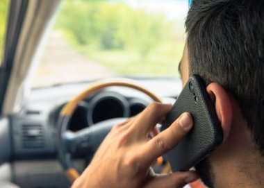 Adam araba sürüyor ve akıllı telefondan geri aranıyor.