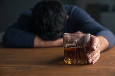 Üzgün adam masanın üstünde alkol bardağı var.