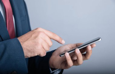 İşadamı Gray Backgroun 'da akıllı telefon kullanıyor.