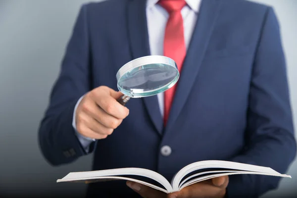 business man hand holding book with magnifie