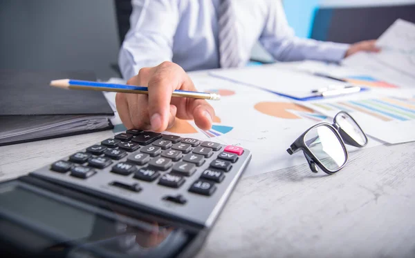 Ds üzerinde hesap makinesi ve belgede çalışan adam