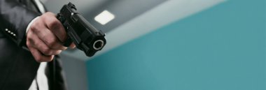 Takım elbiseli bir adam kancaya silah doğrulttu.