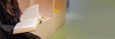 Bayan öğrenci içeride kitap okuyor.