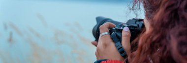 Akşamleyin gölün kenarında elinde kamera olan bir kadın.