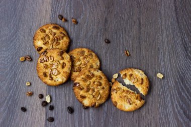 Kahve çekirdekleri ve fındık çevresinde dört kurabiye ile ahşap yüzeyde fıstık kurabiye yalan dağınık