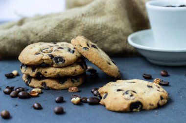 Bir çerez çikolata damla taş bir gemide kahve ve tahıl dağınık fıstık aittir. Yanında bir çuval bezi ve beyaz bir fincan kahve çekirdekleri ile
