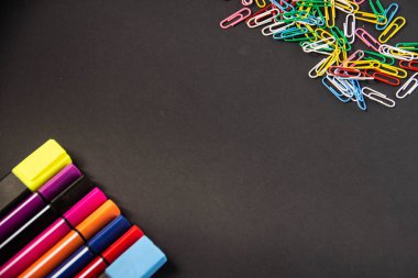 Keçe kalem, kalem, ataç, boya kalemi, cetveller, tutkal, düzeltmen, marker, makas, defter kalemtıraş alanı metin altında siyah bir zemin üzerine