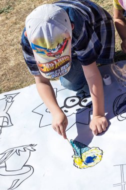 Çocuk bir fırça boya boyama sayfaları beyaz ile boyar.