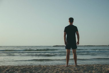 Deniz standları arka plan üzerinde duran ve mesafe içine bakarak bir çekici gencin Retro Fotoğraf