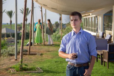 Elinde bir bardak şık bir genç genç erkekle