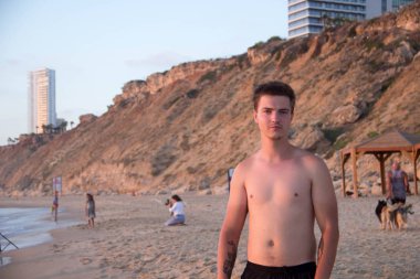 Genç Avrupa biri deniz kenarında elini kolunu sallaya dönüyor ve onu izliyor