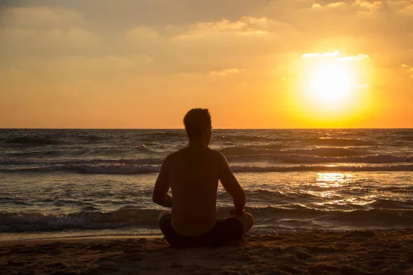 Em um pôr do sol silhueta de fundo de um cara na praia do belo mar — Fotografia de Stock