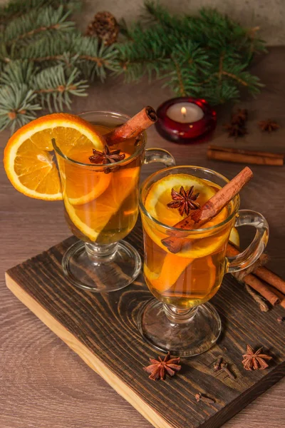 オレンジとキャンドルと見掛け倒しのクリスマス ツリーの枝と木の板にスパイスとグリュー ワインのおいしい香りのよい紅茶を — ストック写真