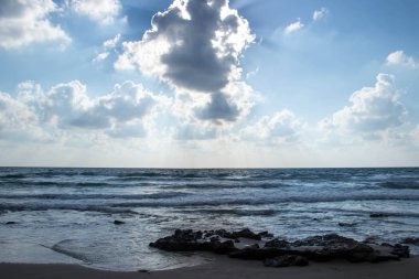 Dalgalar ve kabartma hava bulutlar güneş ışınları ile güzel deniz manzara
