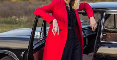 Güzel sarışın kız siyah pantolon ve siyah bir araba poz kırmızı uzun ceket