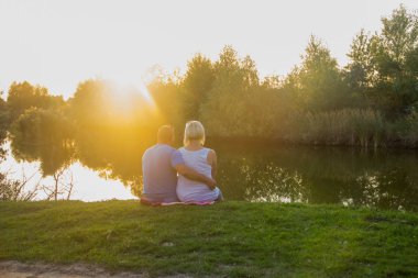 Mutlu çift ayar güneş ışınlarının ormanda gölde kıyısında oturan aşık