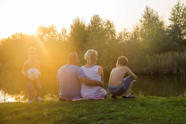 Happy family sit by the lake and watch the sunset