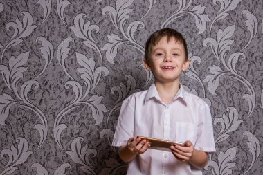 Beyaz gömlekli çocuk elinde bir telefon ile