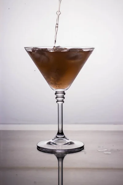 ミラー テーブルに反射で明るい背景にカクテル グラスに液体を注いだ — ストック写真