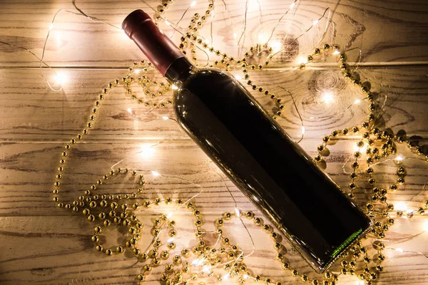 木制背景上的一瓶红酒 拥有金色的装饰和灯光 — 图库照片