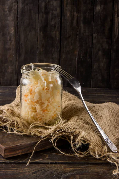 Sauerkraut con zanahorias en un frasco sobre un fondo oscuro —  Fotos de Stock