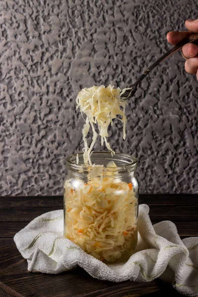 Sauerkraut con zanahorias en un frasco sobre un fondo oscuro —  Fotos de Stock