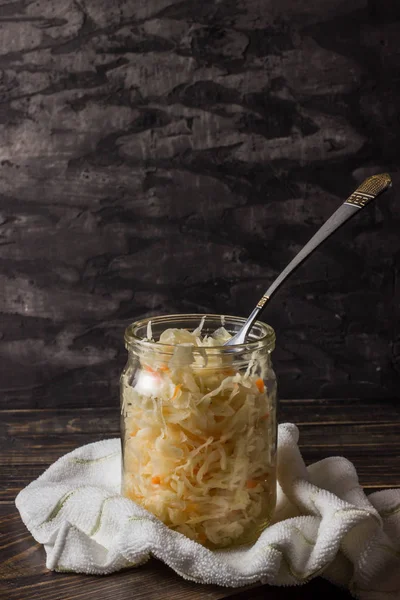 Sauerkraut con zanahorias en un frasco sobre un fondo oscuro —  Fotos de Stock
