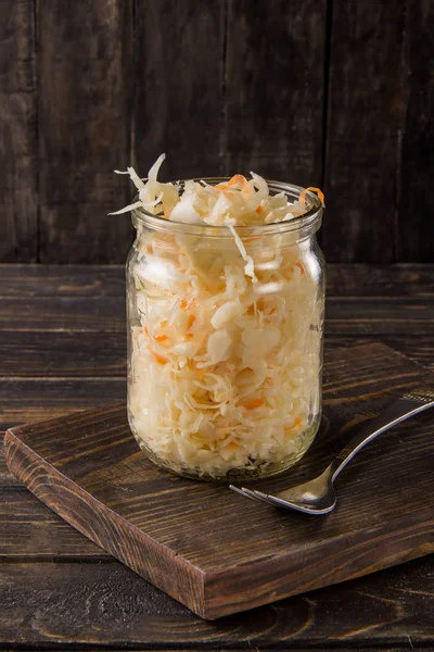 Sauerkraut con zanahorias en un frasco sobre un fondo oscuro —  Fotos de Stock