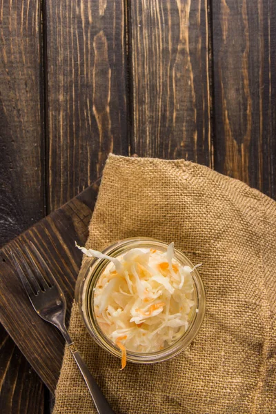 Sauerkraut con zanahorias en un frasco sobre un fondo oscuro —  Fotos de Stock