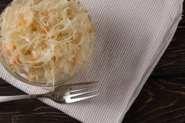 Sauerkraut en un plato de vidrio con un tenedor y gofre blanco sobre un fondo oscuro —  Fotos de Stock