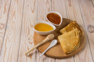 Krep yerken üzerine bal ve reçel hafif bir arka plan üzerinde bir ahşap tahta