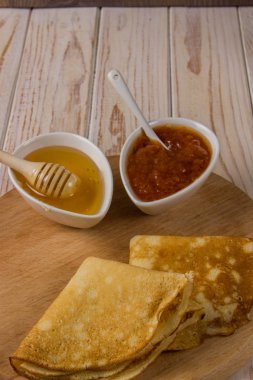 Krep yerken üzerine bal ve reçel hafif bir arka plan üzerinde bir ahşap tahta