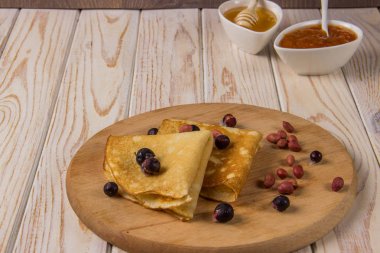 Bal, reçel ve hafif bir arka plan üzerinde meyveleri ile ahşap bir gemide krep