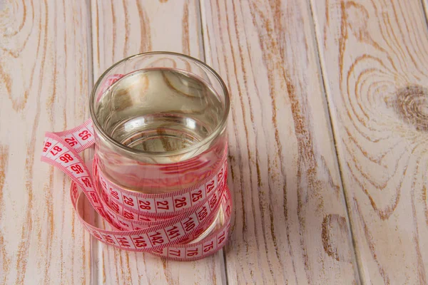 Nastro Misurazione Rosa Con Bicchiere Acqua Uno Sfondo Legno Chiaro — Foto Stock