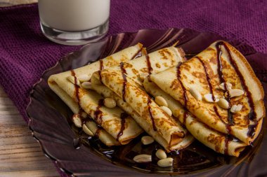 Çikolata soslu bir plaka üzerinde üç krep