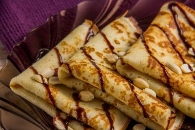 Çikolata soslu bir plaka üzerinde üç krep