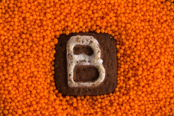 Galletas con letras en el fondo de bolas dulces de naranja —  Fotos de Stock