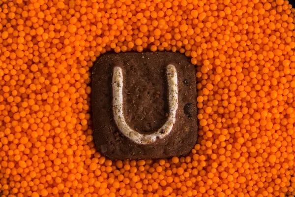 Galletas con letras en el fondo de bolas dulces de naranja —  Fotos de Stock