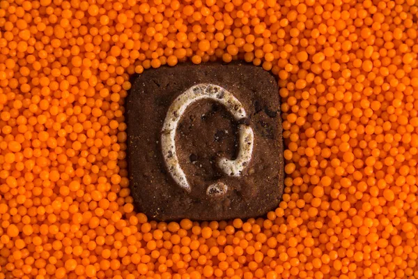 Galletas con letras en el fondo de bolas dulces de naranja —  Fotos de Stock