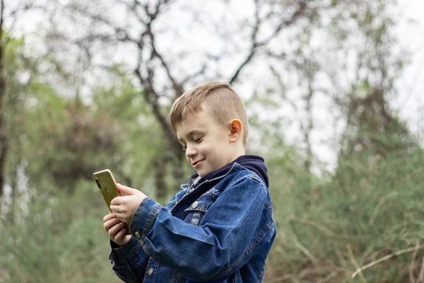 Pojke med en telefon i parken — Stockfoto