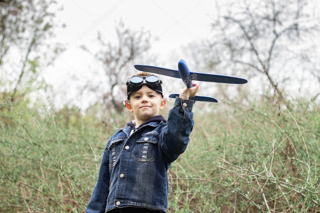 The boy launches a blue plane into the sky in a dense forest