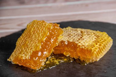 Taş bir tahtaya bal peteği dök, organik ürün.