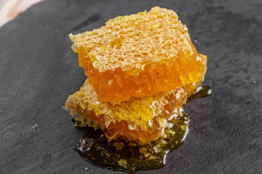 Taş bir tahtaya bal peteği dök, organik ürün.